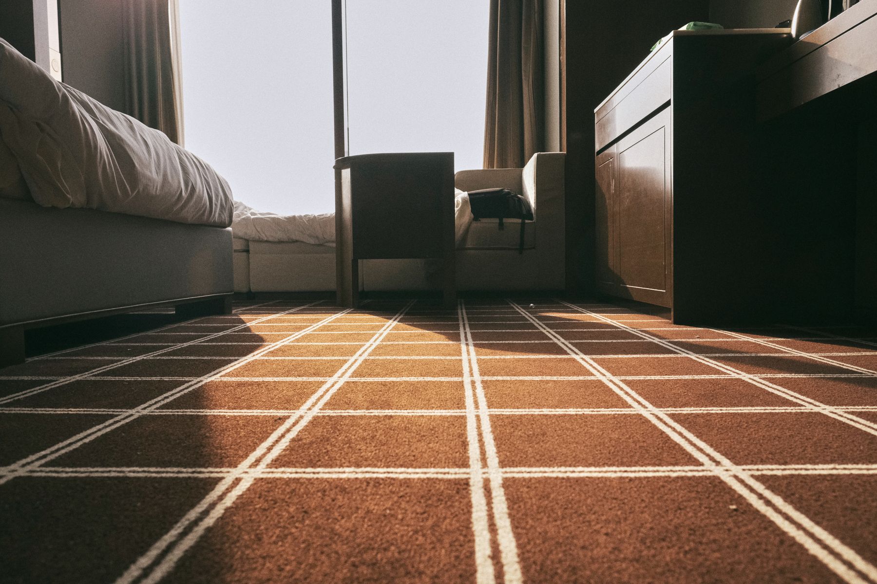 Sunlit bedroom with patterned wall-to-wall carpet